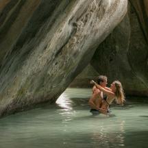 two people standing in the water in a cave