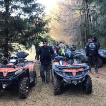 a man standing next to two atvs on a dirt road