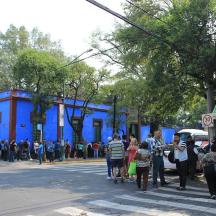 un gruppo di persone che camminano lungo una strada con un edificio blu
