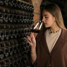 a woman drinking a glass of wine next to a wall
