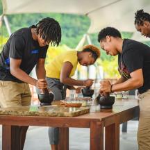 a group of people standing around a table making pottery