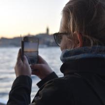 a woman taking a picture of the water with her cell phone