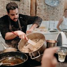 a man in a kitchen preparing food in a pan