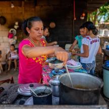 a woman cooking food in a pot on a stove