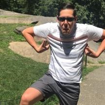 un bărbat purtând ochelari de soare, un tricou alb și pantaloni scurți
