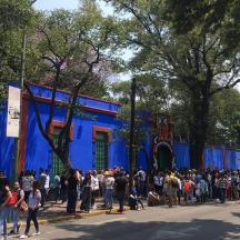 Una multitud de personas de pie frente a un edificio azul.