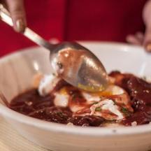 a person eating a bowl of food with a spoon