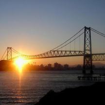 a bridge over the water with the sunset in the background
