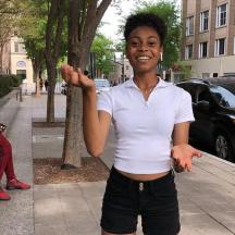 a young woman standing on a sidewalk with her hand up