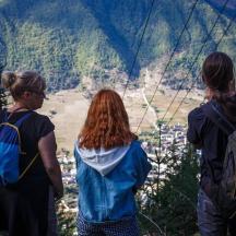 Drei Frauen stehen auf einem Berg und blicken in ein Tal