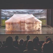 an audience watching a stage with a tent on it