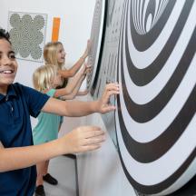 a boy pointing to a target on a dartboard