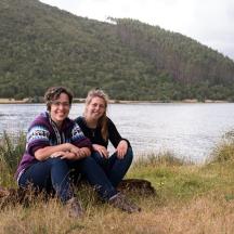 dues persones assegudes en una roca al costat d'un llac