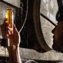 Un hombre sosteniendo una botella frente a una pared.