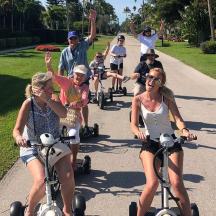 a group of people riding on scooters down a sidewalk