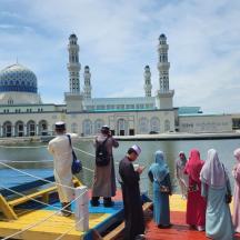 a group of people standing on a dock in front of a mosque