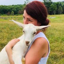 seorang wanita memegang kambing putih di padang