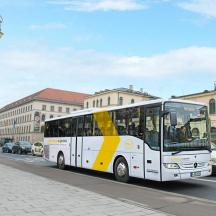 Žlutobílý autobus jedoucí po městské ulici