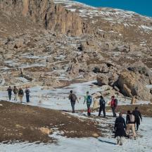 eine Gruppe von Menschen, die im Schnee in der Nähe eines Berges spazieren gehen