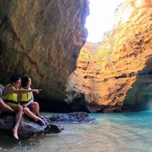two people sitting on a rock in a cave