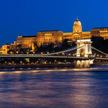 a bridge over a river in front of a large building