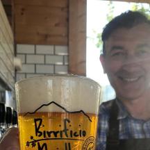 ein Mann lächelt hinter einem Glas Bier