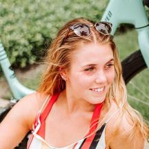 a woman with sunglasses on her head sitting next to a bike
