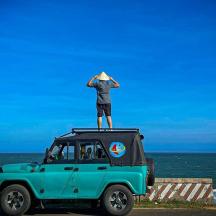 a man standing on the roof of a blue jeep
