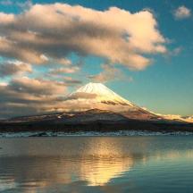 a snow covered mountain in front of a body of water