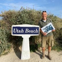 a man standing next to a sign that reads watch beach