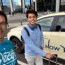 two men standing in front of a car