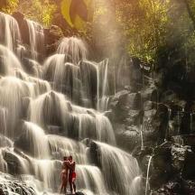two people standing in front of a waterfall