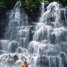 a woman sitting in front of a waterfall
