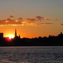 a city skyline with the sun setting over the water