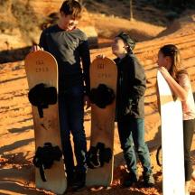 drei junge Leute stehen mit Skateboards im Sand