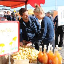 a man and a woman looking at fruit at a market