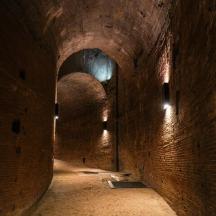 a dark brick tunnel with two tunnels with lights