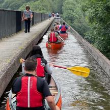 eine Gruppe von Menschen in Kajaks auf einem Fluss