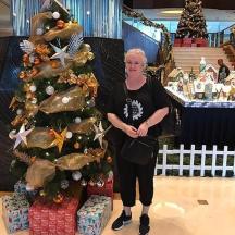 a woman standing next to a christmas tree in a store