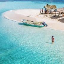 una persona dreta a la platja amb una barca a l'aigua