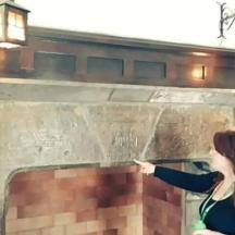 a woman pointing at a brick fireplace