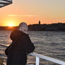 a woman standing on a boat looking at the sunset