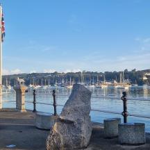 a large rock in front of a harbor with boats