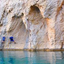 three people walking on a cliff near the water