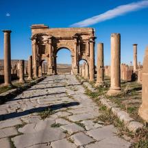 ancient ruins with an arch and a stone road