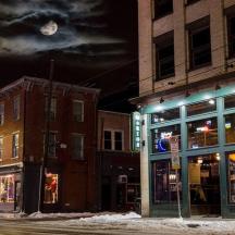 a city street at night with buildings and a clock