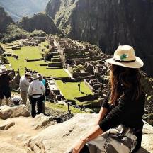 a woman standing on top of a mountain looking at a city