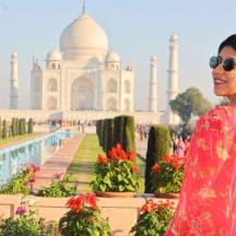 a woman standing in front of the taj mahal