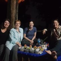 a group of people sitting around a table with cupcakes