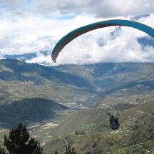 a person flying a parachute over a valley